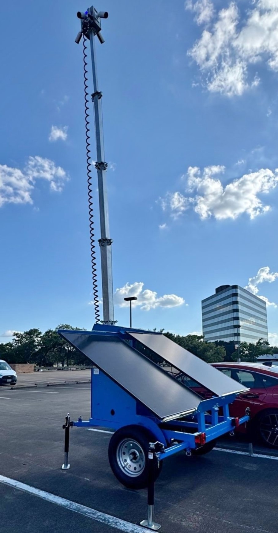 Blue mobile surveillance trailer with raised CCTV camera mast and solar panels